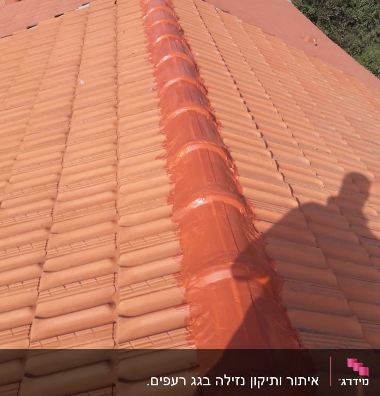 רעפים כתומים עם חומר איטום על קו הרכס